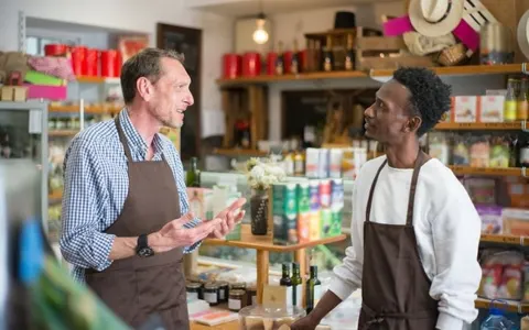 Two shop employees in aprons talking in a grocery store